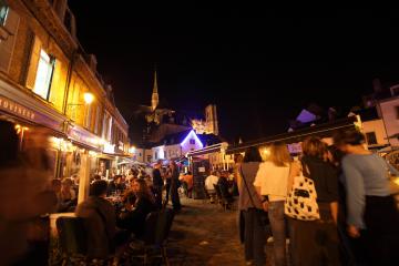 Vue de nuit sur la place du Don dans le quartier Saint-Leu.Des personnes boivent un verre en terrasse.