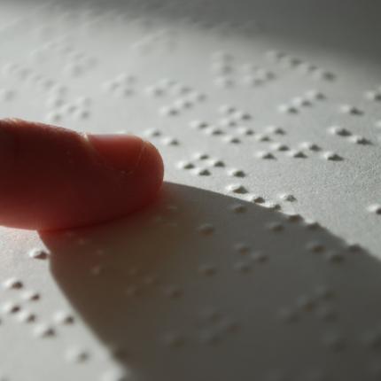 Photo du doigt d'une personne lisant un document en braille