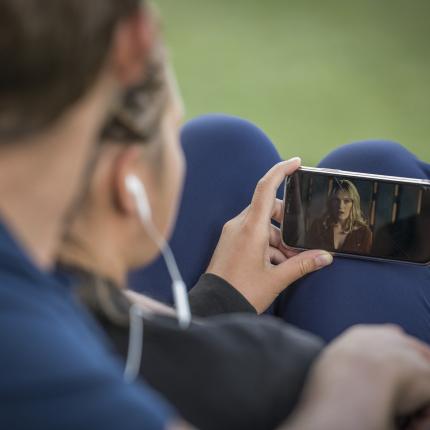 Photo d'un homme assis regardant une vidéo sur son smartphone.
